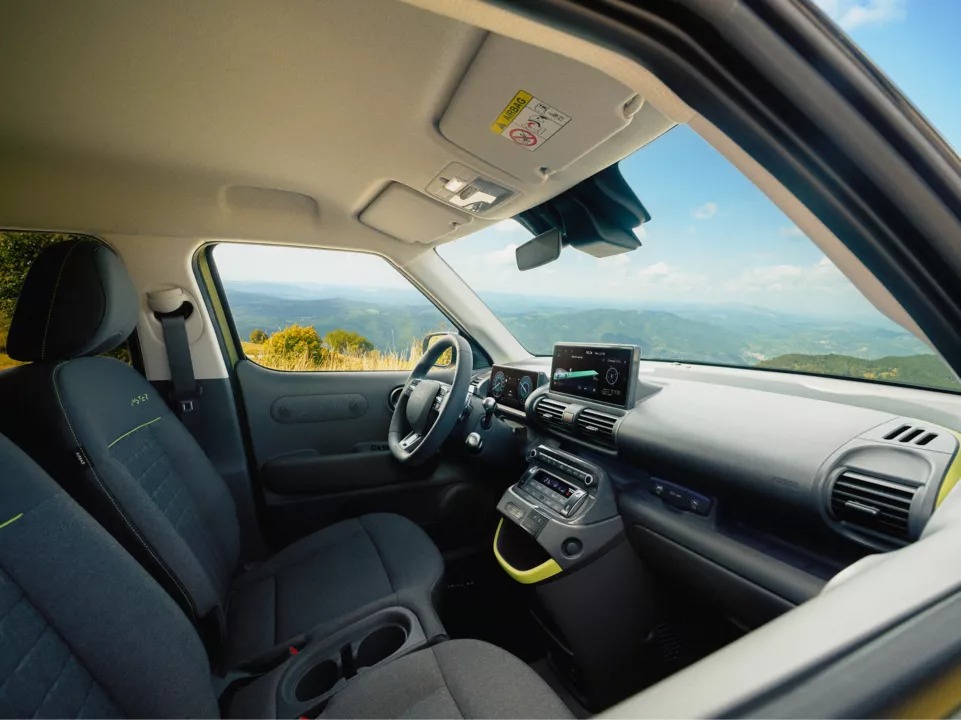 Interior of a modern car showing dashboard and seats with a landscape view through the window.