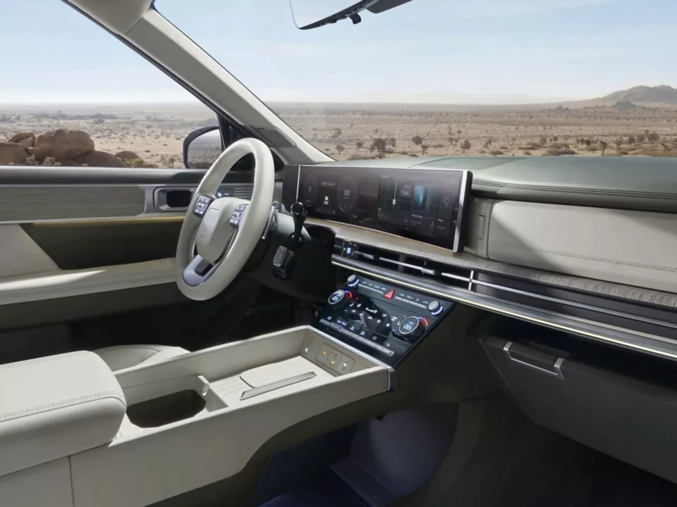 Interior of a modern vehicle with a touchscreen dashboard and a light-coloured steering wheel.