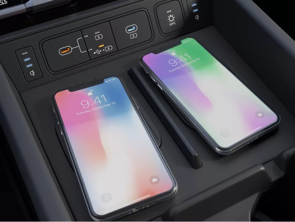 Two smartphones charging wirelessly in a car console with charging indicators.