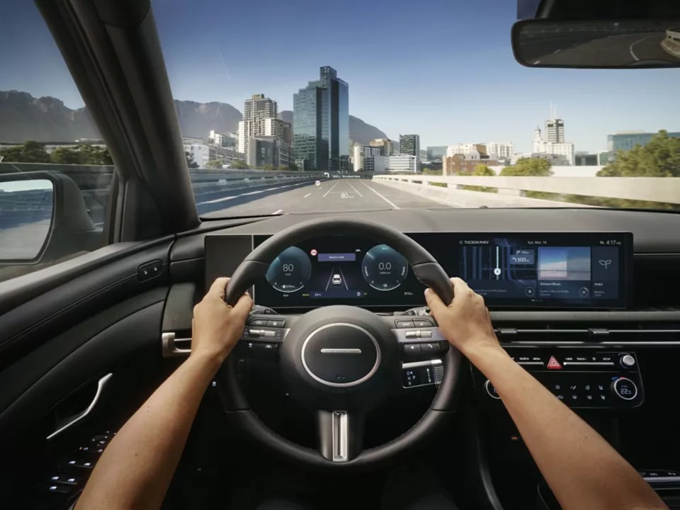 Person steering modern car, digital dashboard displaying speed and navigation.