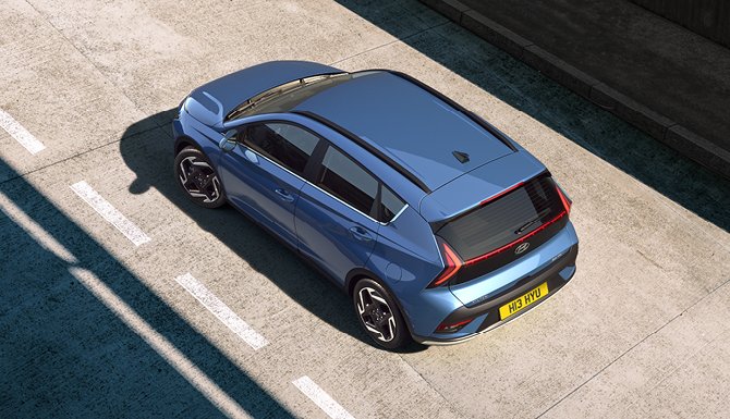 Blue car viewed from above, parked on a road with white dividing lines.