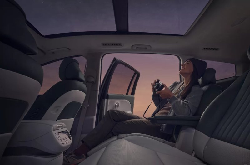 Person with a camera sits in a parked car, looking up through the sunroof.