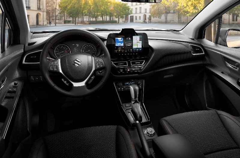 Interior of a Suzuki car showing steering wheel and dashboard controls.