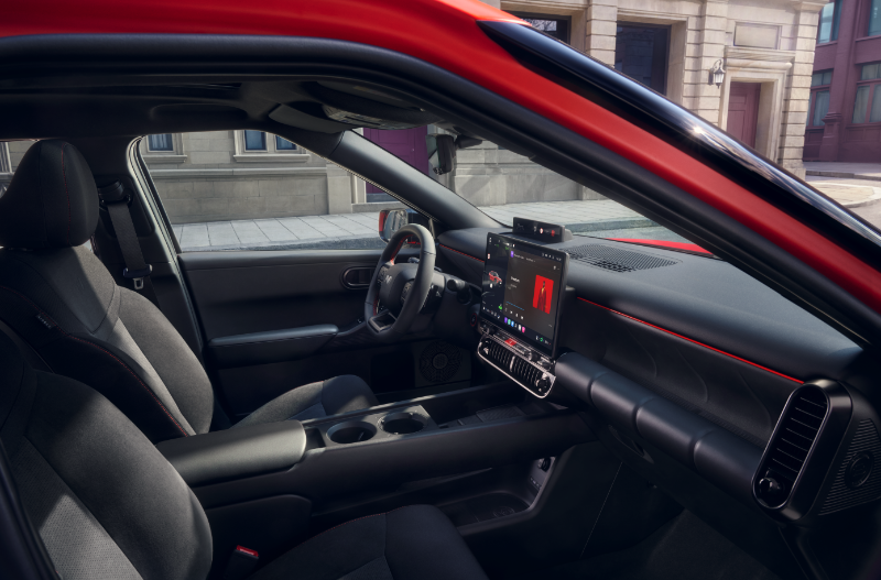 View of front seats and dashboard inside a red car with touchscreen display.