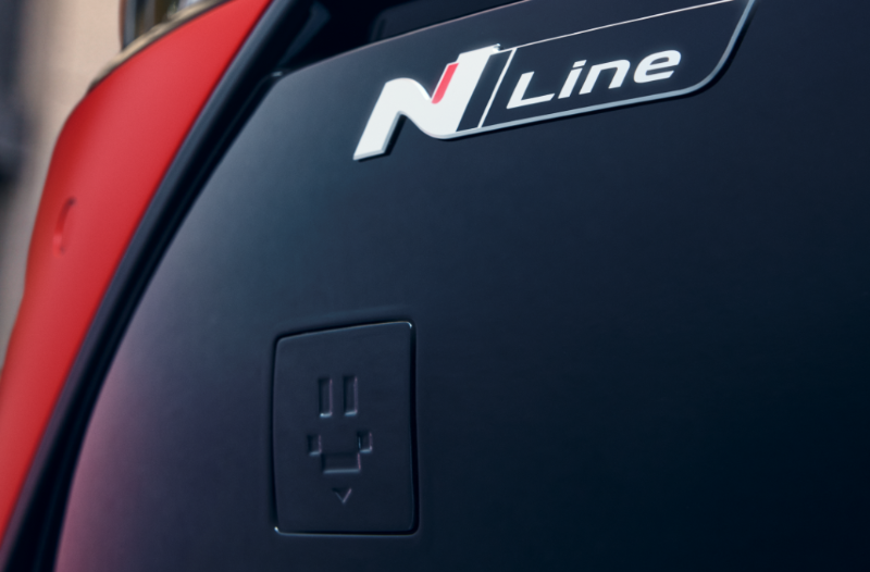 Close-up of a car's N Line badge above an electronic charge point cover.