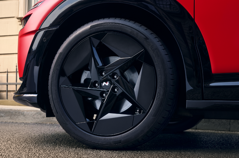 Close-up of a car's black alloy wheel with a geometric design and visible tyre wall.