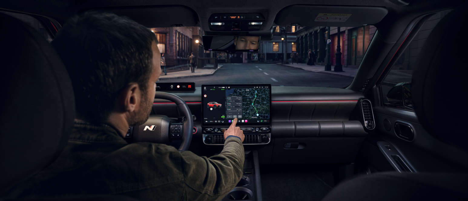 Driver using touchscreen navigation in a car interior at night.