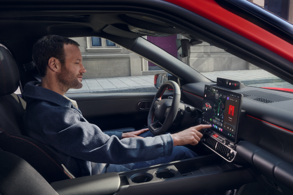Man using touchscreen dashboard in a red car's interior.