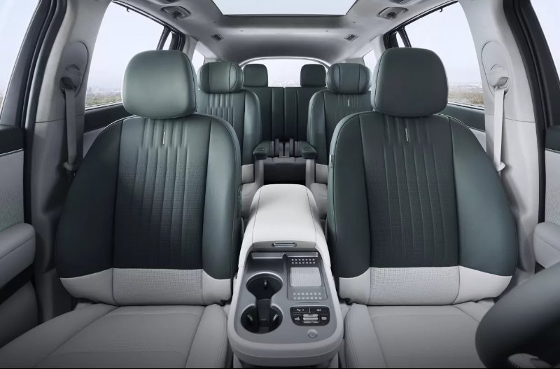 Interior view of a car showing five seats and central console with cup holders.