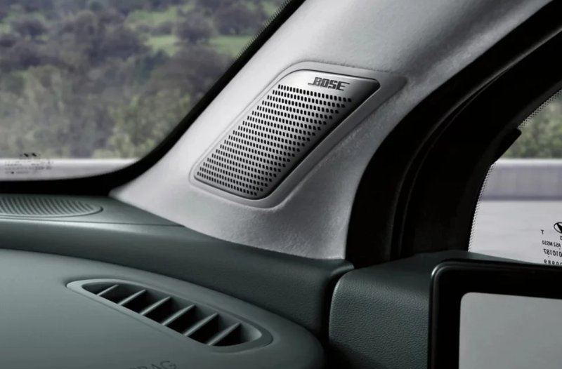 Car's interior with a Bose speaker on the pillar and an air vent on the dashboard.