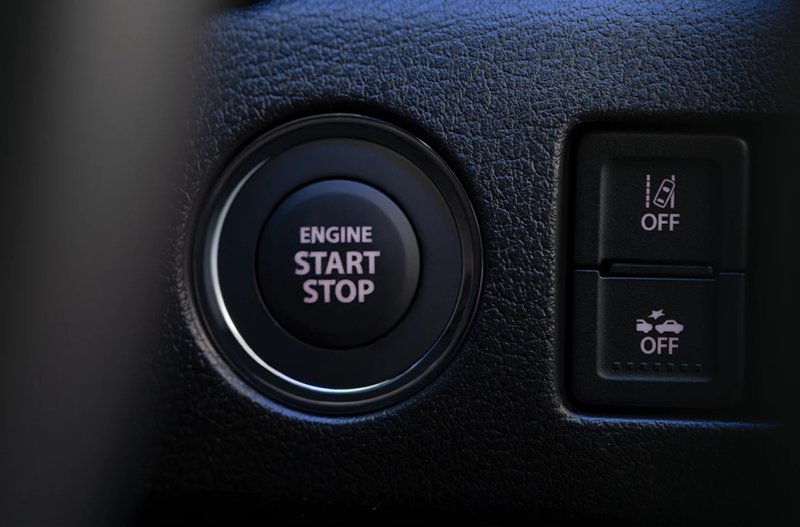 Close-up of a car start-stop button and adjacent control switches.