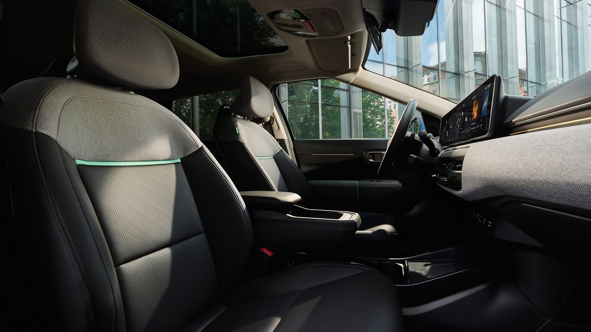 Modern car interior with two front seats and a dashboard display screen.