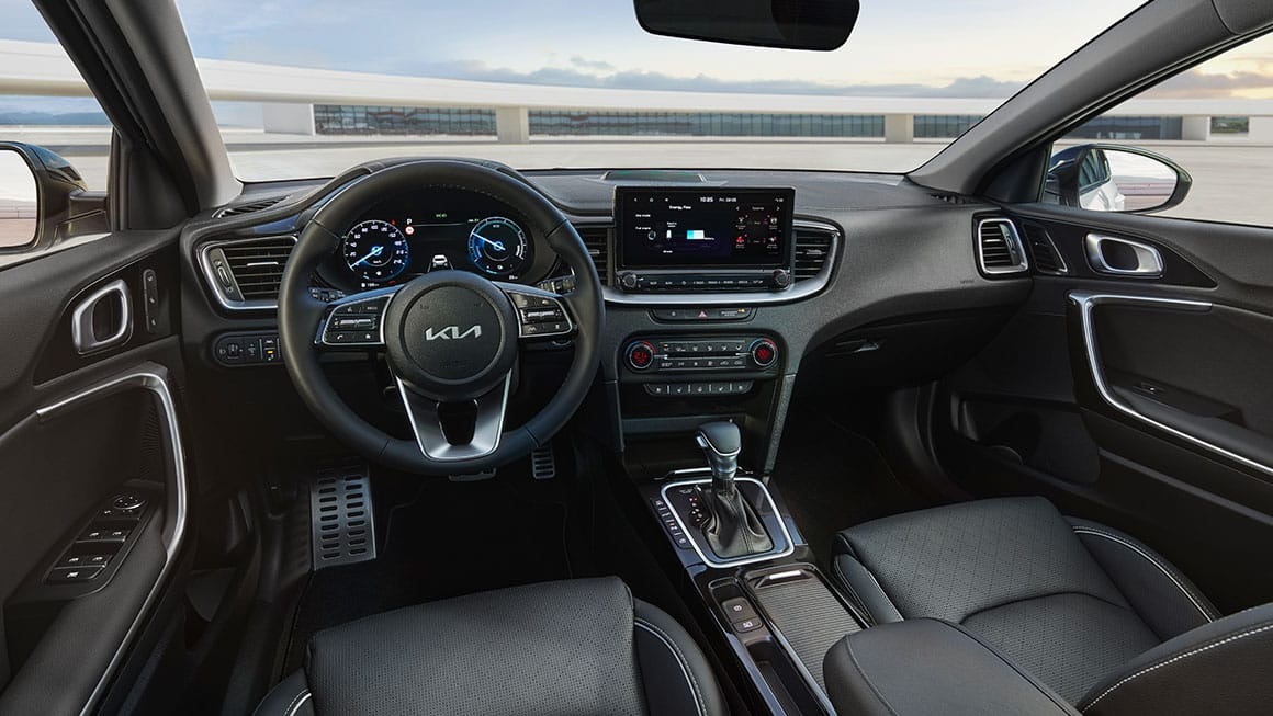 Car interior showing steering wheel, digital dashboard, and central touchscreen display.