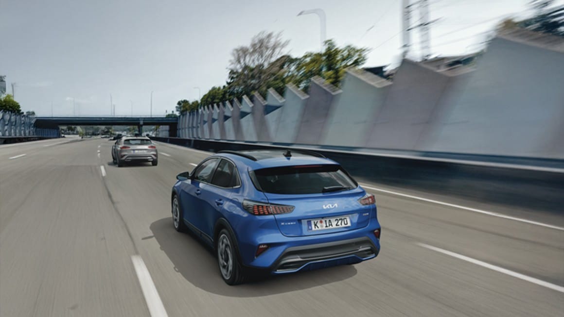 Blue car driving on a motorway next to another vehicle.