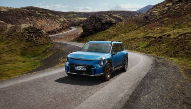 Blue SUV driving on a curving mountain road.