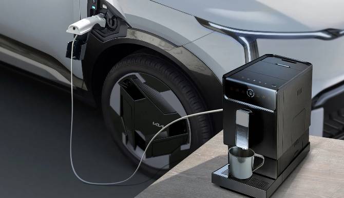 Electric vehicle powering a coffee machine via charging cable.