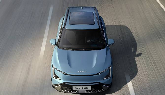 Top view of a blue car with a sunroof driving on a road.