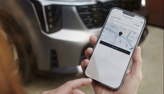 Person holding a smartphone displaying a map app near a car.