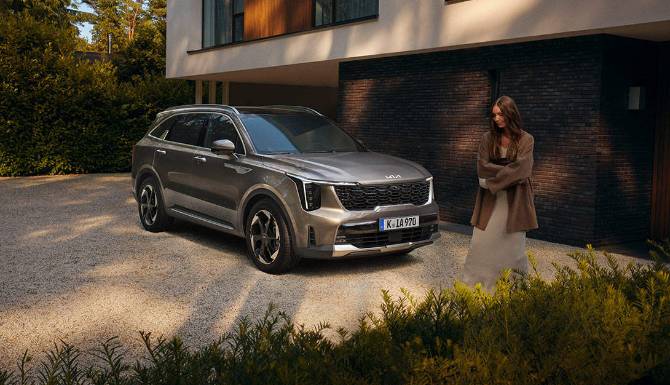 Silver SUV parked outside a modern house, with a person walking nearby.