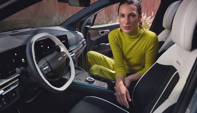 Woman in a green top seated in a car with a modern interior design.