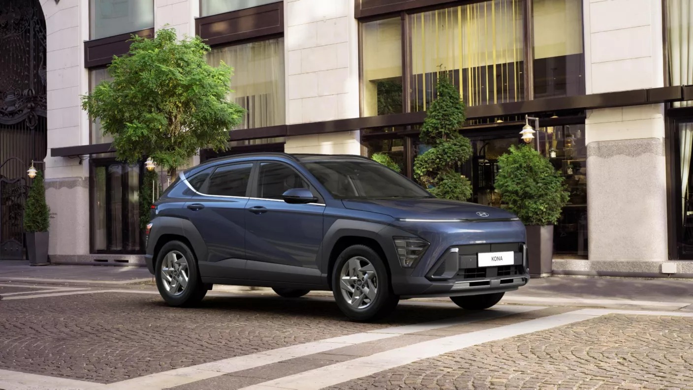 Blue SUV parked on tiled street in front of building with greenery.