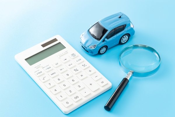 Calculator, toy car, and magnifying glass arranged on a blue surface.