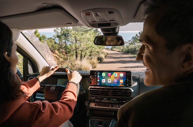 man and woman in front seats laughing and driving down the road