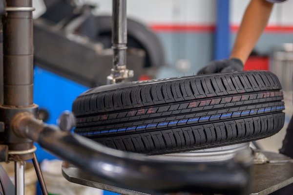 Mechanic aligning tyre on a mounting machine