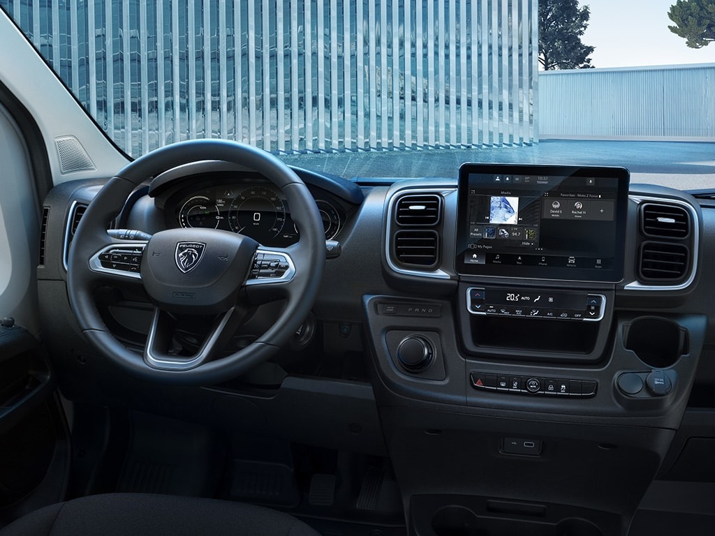 Peugeot car dashboard with steering wheel and touchscreen display.