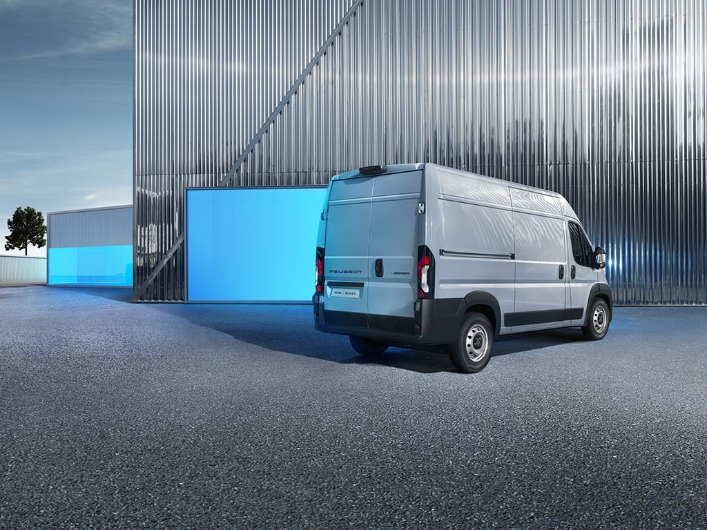 Silver van parked outside a large corrugated metal building.