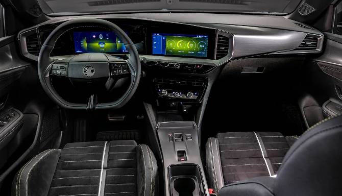 Car interior with digital dashboard, two-tone seats, and steering wheel.