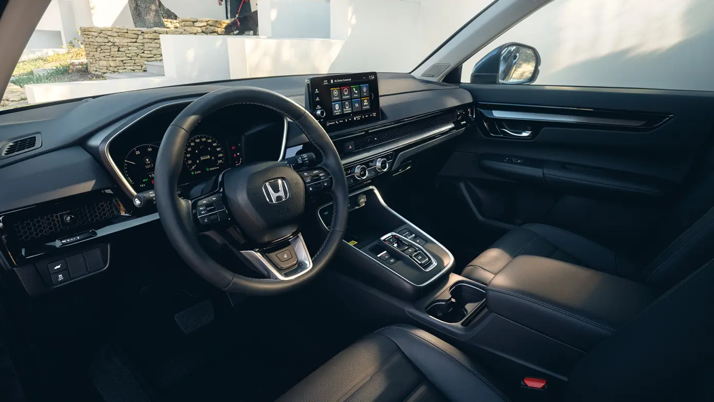 Interior of a Honda car showing the steering wheel and dashboard controls.