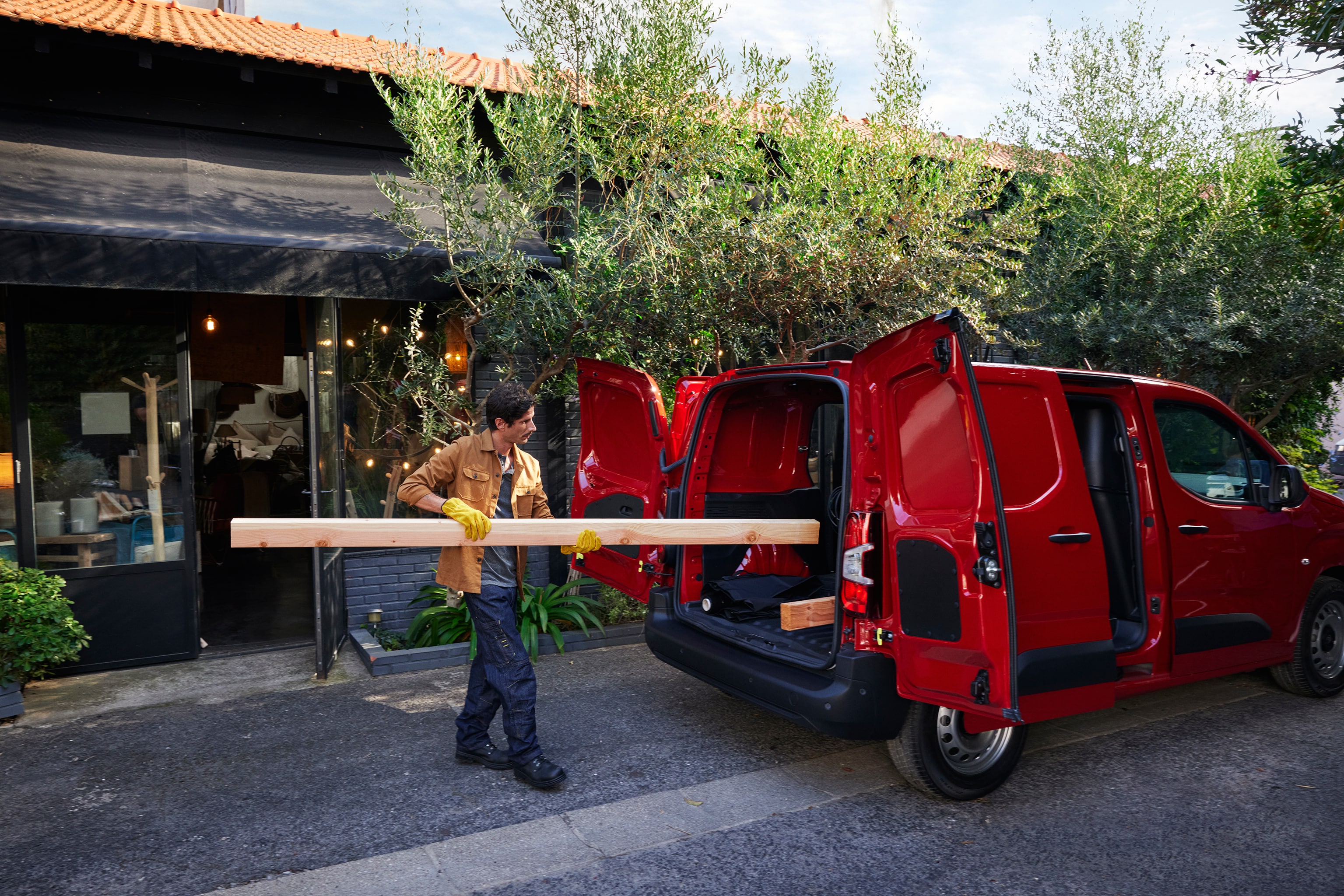 Person loading a wooden plank into a red van.