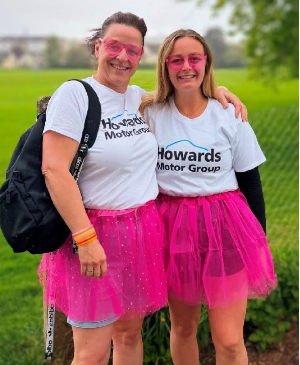 Two people wearing matching t-shirts and pink tutus, both smiling at the camera.