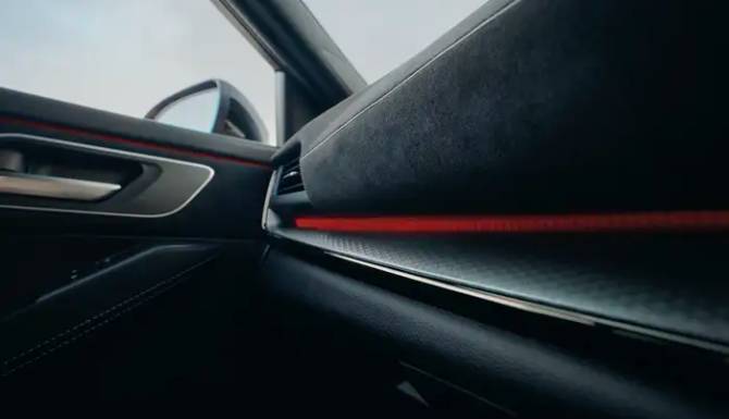 Car interior with a view of the door handle and red accent lighting.