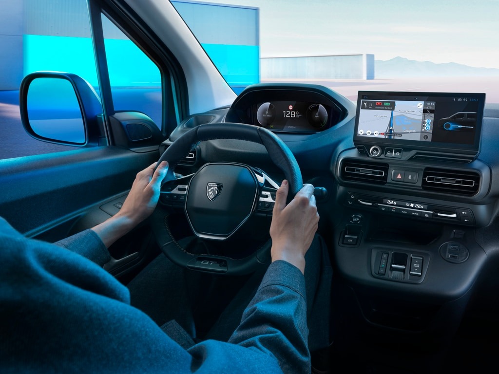 Driver holding the steering wheel of a car with a digital dashboard and navigation screen.