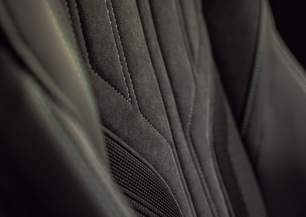 Close-up of a car seat with black suede and fabric upholstery.
