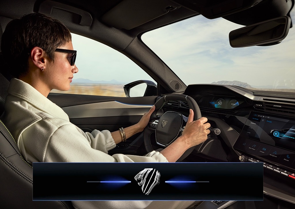 Person driving a car, holding the steering wheel, with a digital dashboard display.