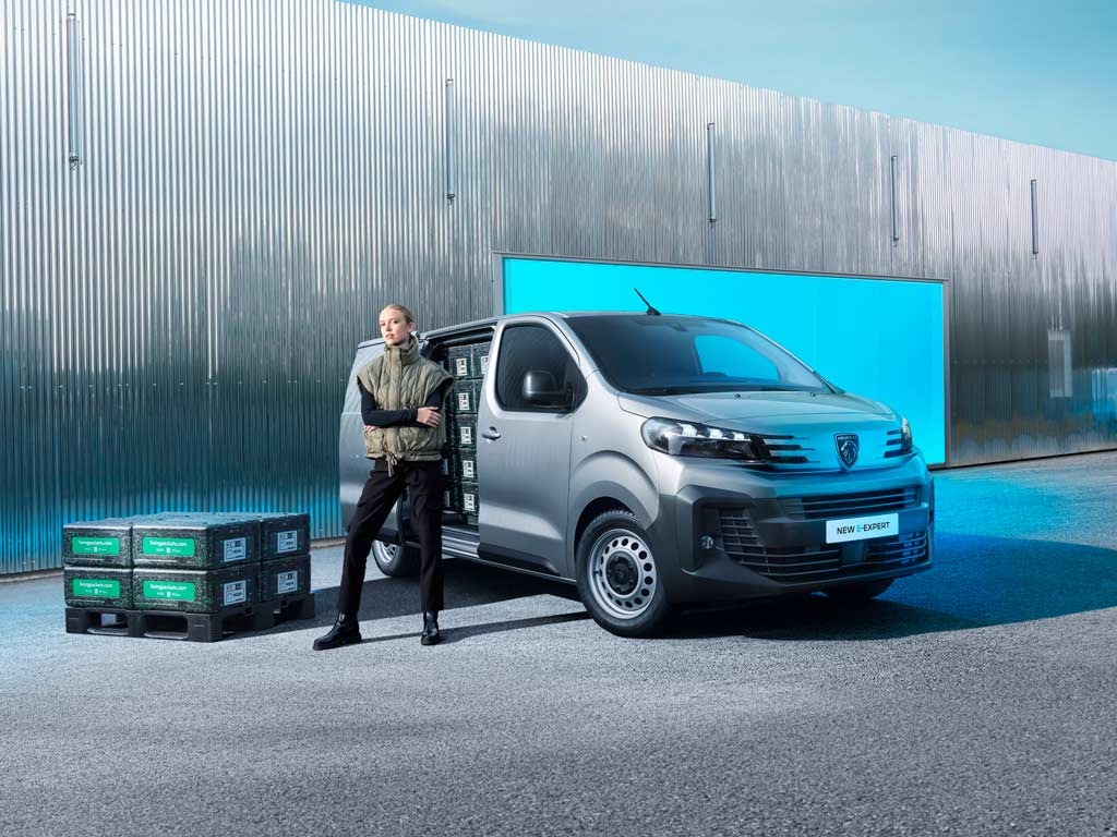 Person leaning on a van with open side door, crates stacked nearby.
