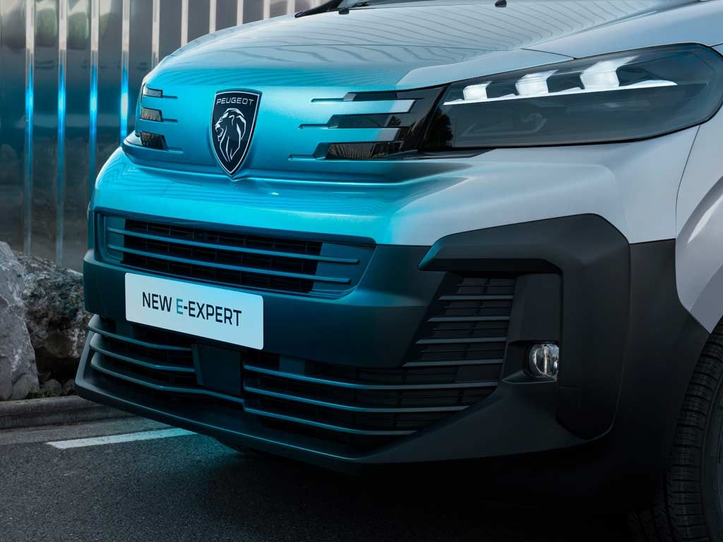 Front view of a Peugeot E-Expert van with headlights on.