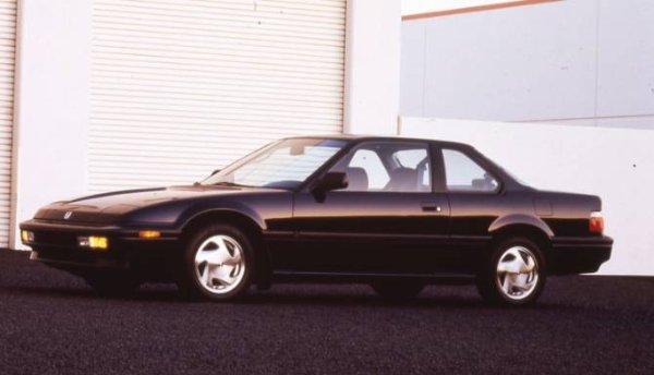 Dark-coloured 1980s coupe parked on a dark surface with visible car details.