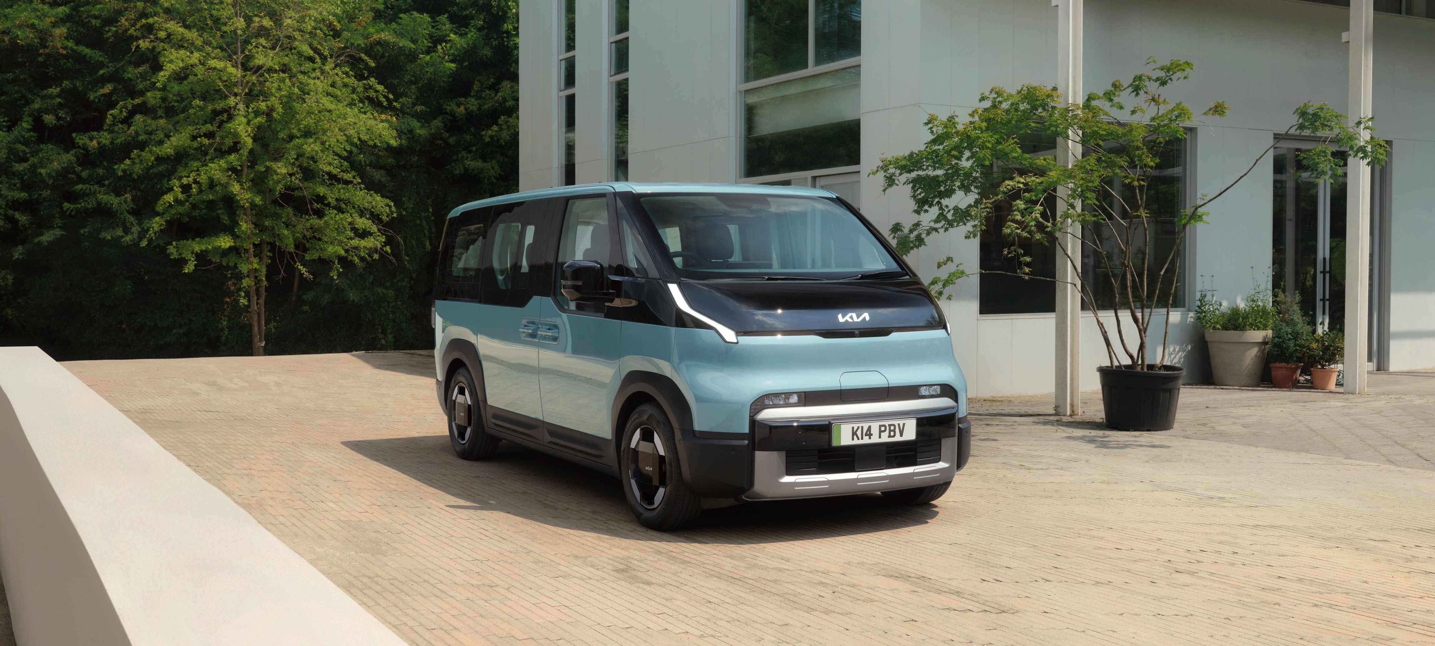 A blue van parked outside a modern glass-fronted building.