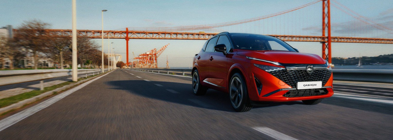 Qashqai on the road with an orange bridge behind it