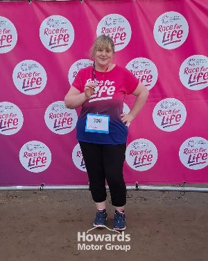 Participant in a Race for Life event, wearing a pink shirt and holding a medal.