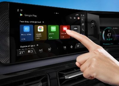 Finger pressing an app icon on a car touchscreen displaying various media apps.