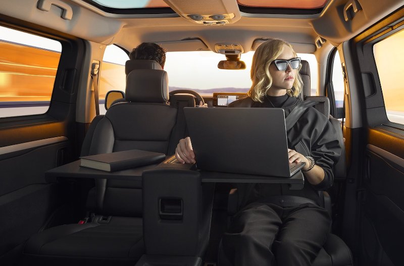 woman sat in the car facing backwards on computer