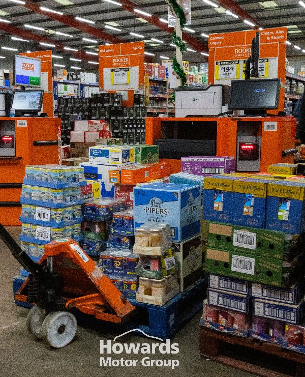 Boxes of assorted goods on a pallet truck in a wholesale store aisle.