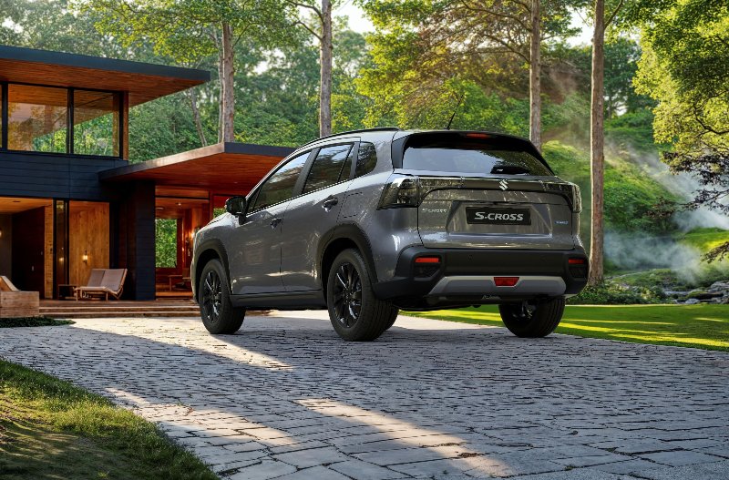Silver SUV parked on a stone driveway beside a modern house with large glass windows.