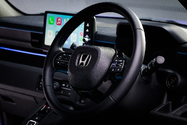 Honda car steering wheel with control buttons and a digital screen in the dashboard.