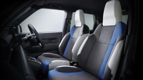Car interior with grey, blue, and white seats and a black steering wheel.